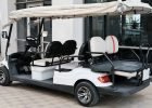 Electric buggy near hotel building. White golf cart with back seats waiting for passengers.