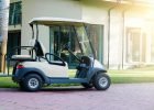 Outdoor recreation. A white golf cart is parked near the modern cottage house. Electric car in the parking lot of the resort area. Recreation, Summer vacation concept